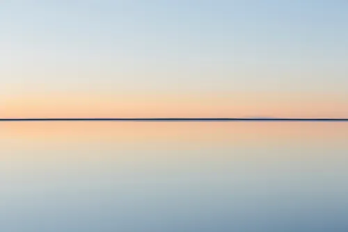 Calm sea horizon at sunset under a pastel sky