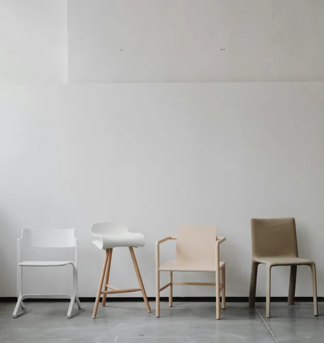 Four different chairs lined up against a white wall