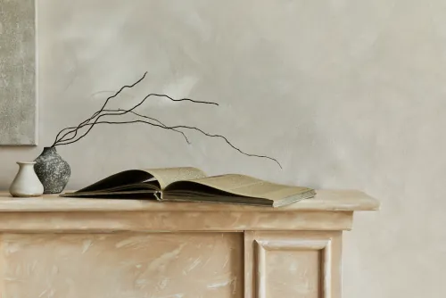 Open book, vase with twigs and ceramic jug on a stone mantelpiece