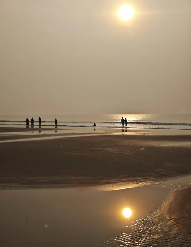 People on a wide beach at low tide under a hazy sun