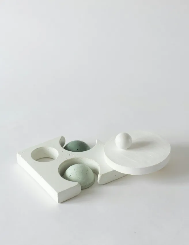 White sculptural plinth holding green and white spheres